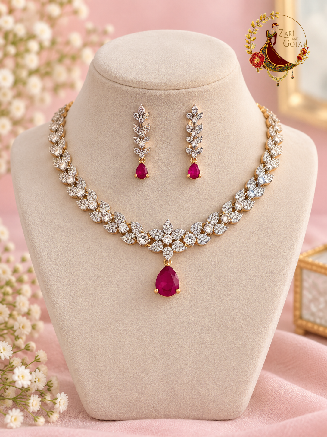 Gold-tone American diamond leaf-cluster necklace with ruby pear drop and matching earrings on a display bust, Zari and Gota UK