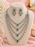 Four-layer silver-tone American diamond necklace with emerald green ovals and statement earrings on a display bust, Zari and Gota UK