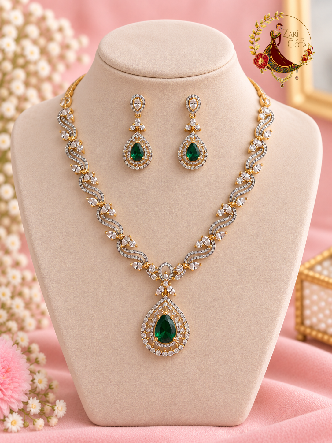 Gold-tone American diamond wave necklace with emerald green pear pendant and matching earrings on a display bust, Zari and Gota UK