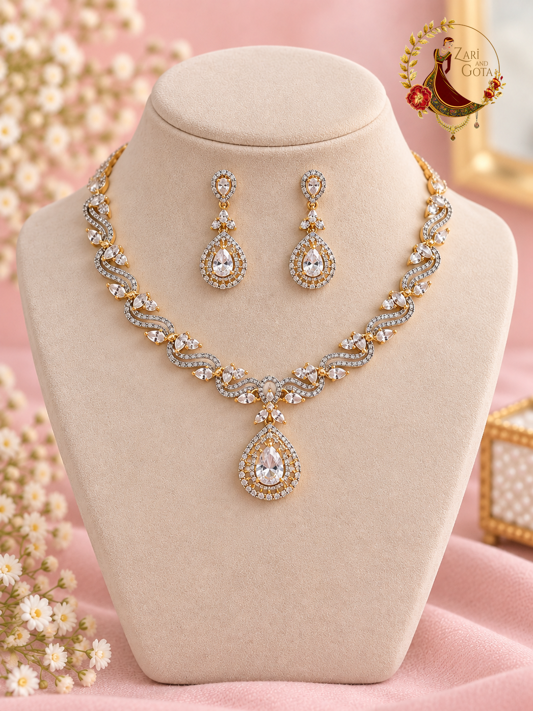 Gold-tone American diamond wave necklace with clear pear pendant and matching earrings on a display bust, Zari and Gota UK