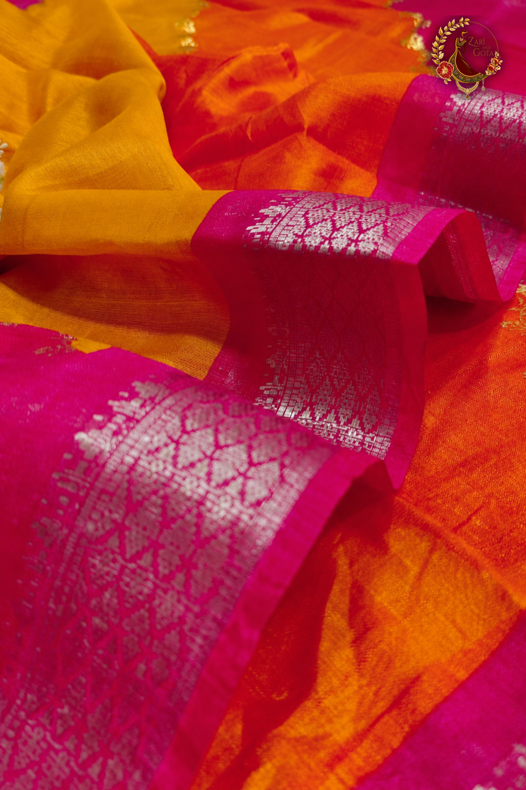 Close detail of silver zari woven Banarasi border on pink and orange cotton silk saree