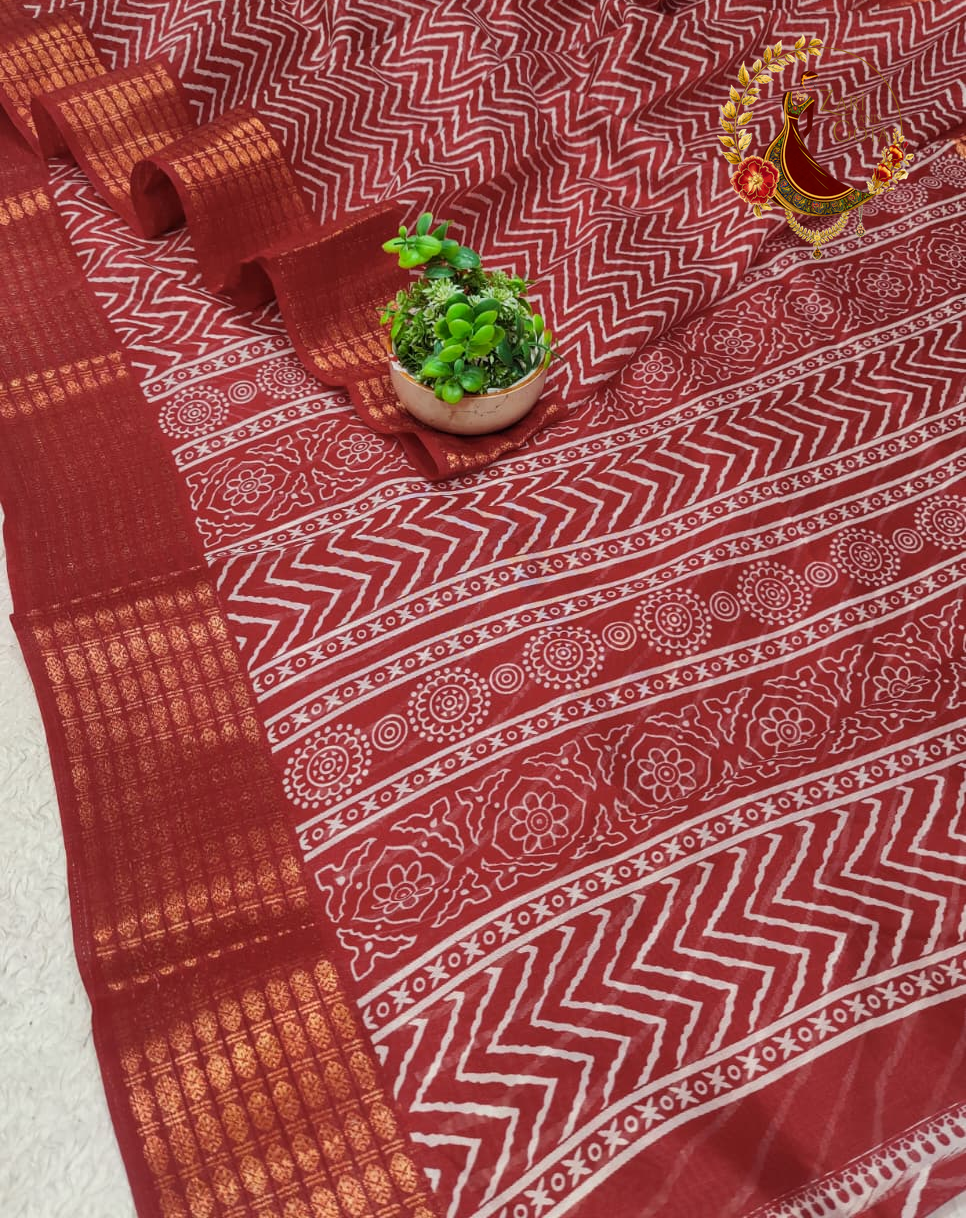 Folded maroon cotton silk saree showing the woven gold zari border blocks
