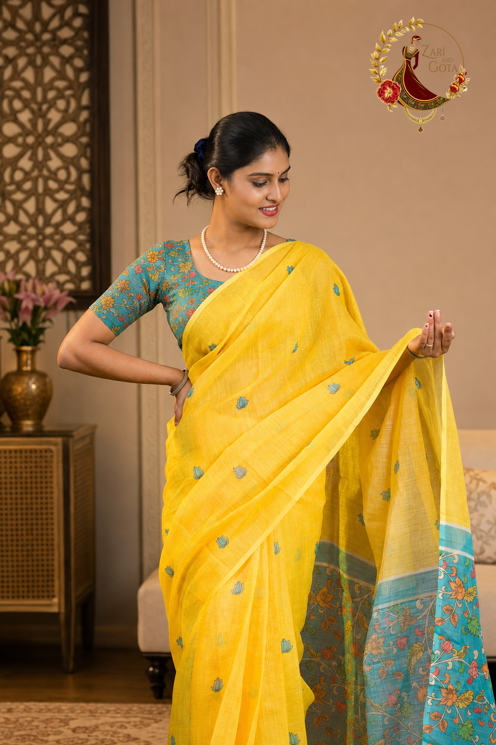 Model holding out the pallu of a yellow kalamkari cotton saree showing the teal floral border