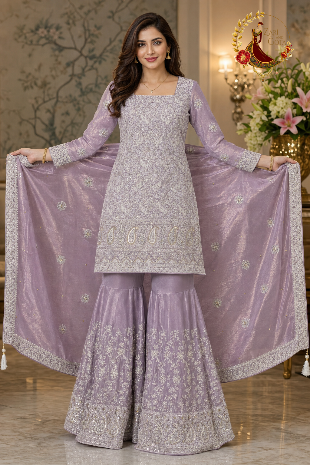 Lavender tissue silk embroidered suit styled as a short kameez with sharara and the dupatta held open across the back, worn by a model, Zari and Gota UK